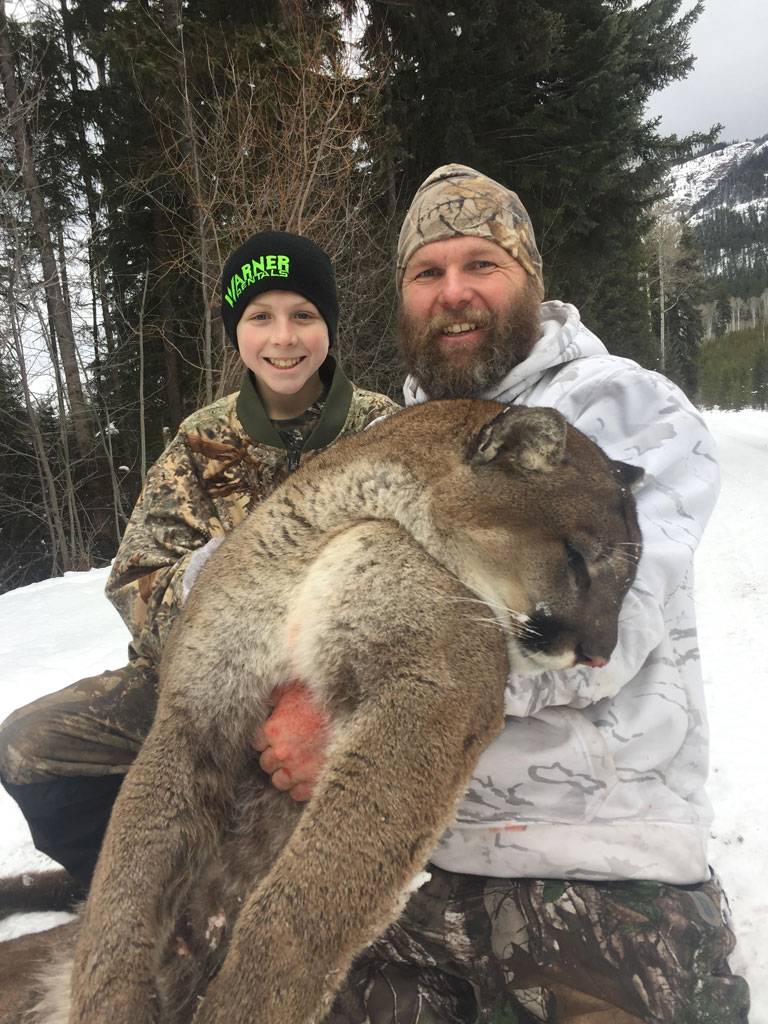 A father and son posing with a cougar (mountain lion)