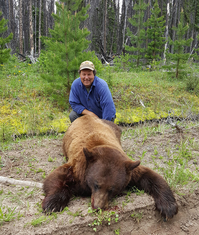 Happy hunter posing with a large cinnamon phase black bear.